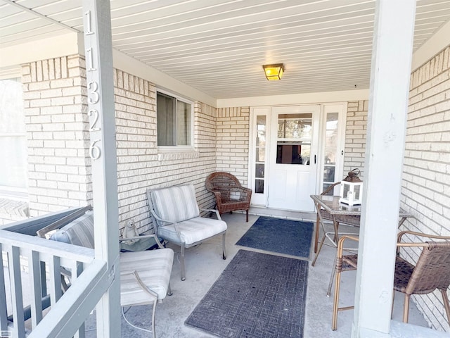 doorway to property featuring covered porch and brick siding