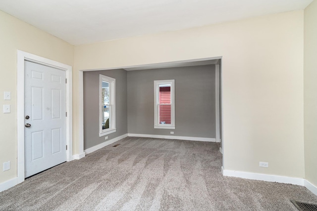 carpeted spare room with visible vents and baseboards