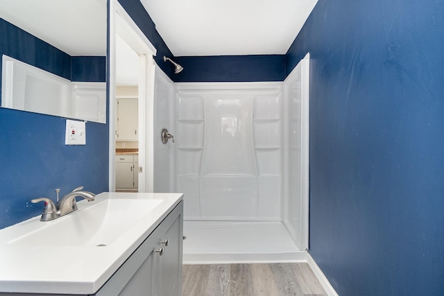 bathroom with baseboards, walk in shower, wood finished floors, and vanity