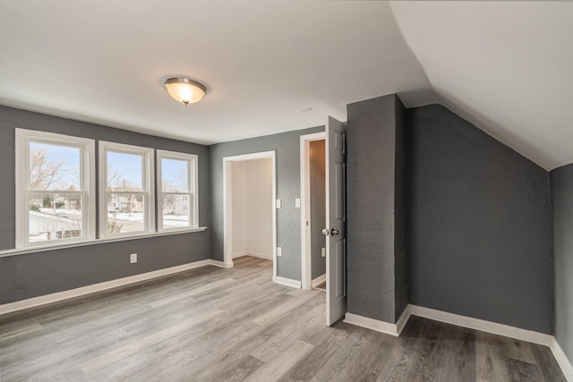 unfurnished bedroom with baseboards, vaulted ceiling, and wood finished floors