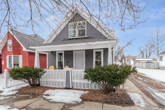 view of front of house with covered porch, a shingled roof, and fence