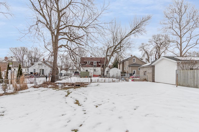 yard layered in snow with a residential view and fence