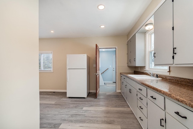 kitchen featuring light wood finished floors, recessed lighting, freestanding refrigerator, a sink, and baseboards