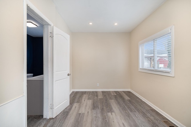 empty room featuring recessed lighting, wood finished floors, visible vents, and baseboards