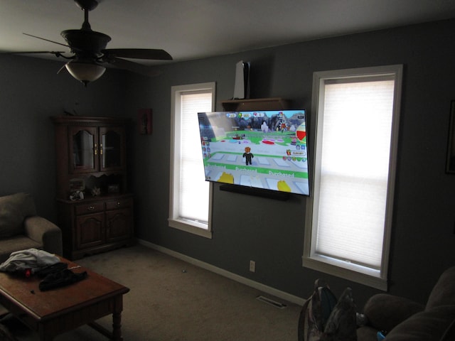 living room featuring a ceiling fan, light colored carpet, visible vents, and baseboards