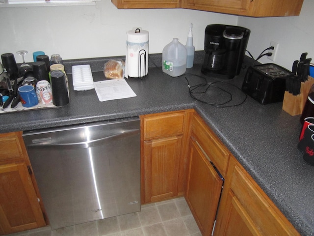 kitchen with dishwasher, dark countertops, and brown cabinets