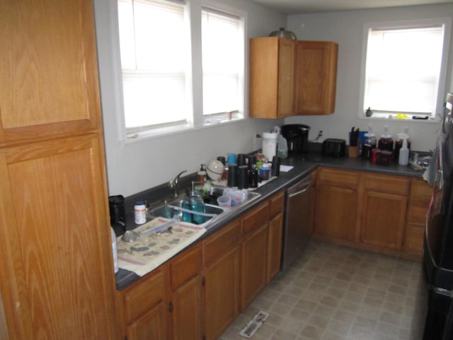 kitchen featuring a sink, brown cabinets, stainless steel dishwasher, and freestanding refrigerator