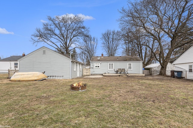 rear view of house with a fire pit, a yard, a wooden deck, and fence