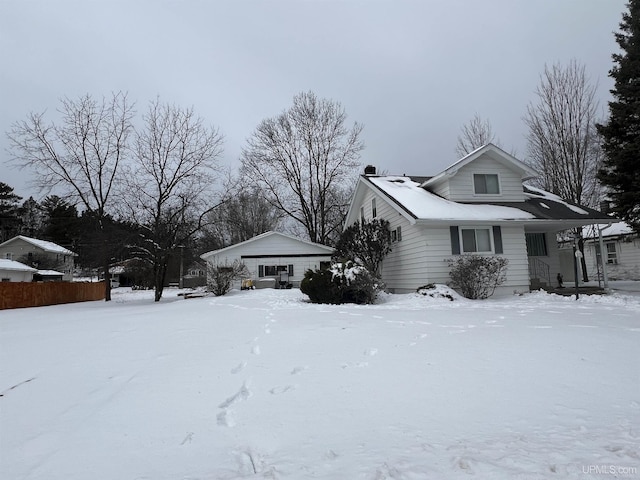 view of snowy exterior featuring a garage and fence