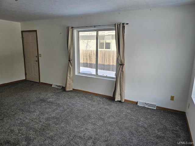 carpeted empty room featuring visible vents, a textured ceiling, and baseboards