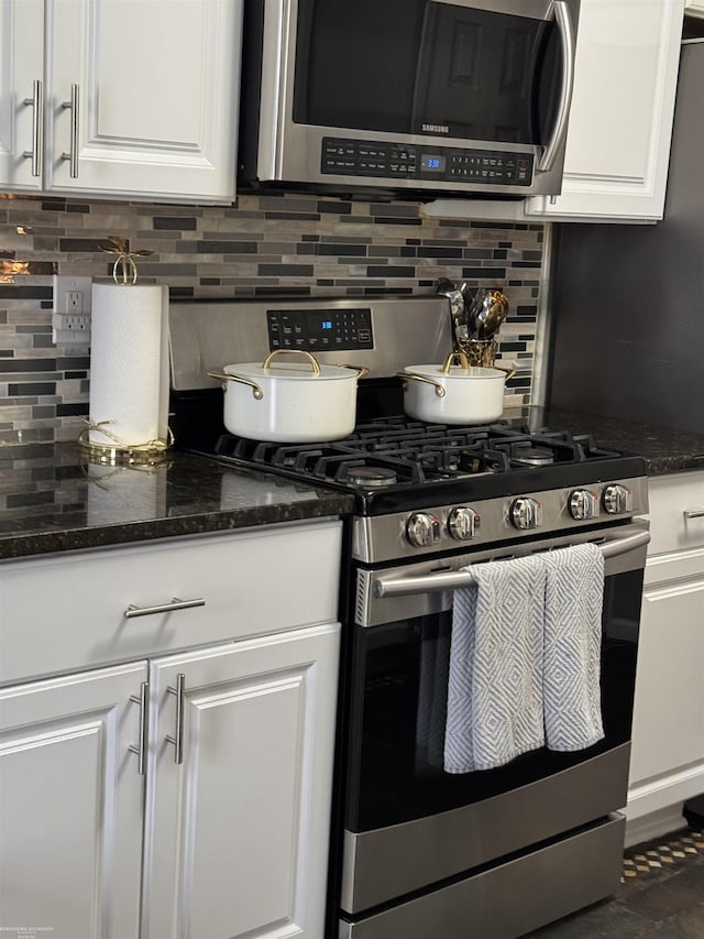 kitchen featuring white cabinets, dark stone counters, stainless steel appliances, and decorative backsplash