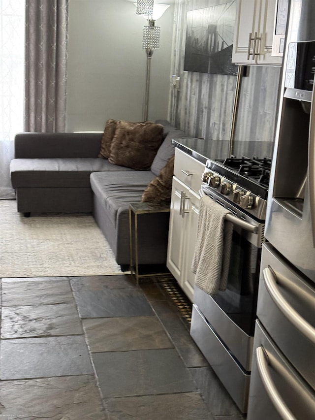 kitchen featuring stainless steel gas range, fridge, and white cabinets