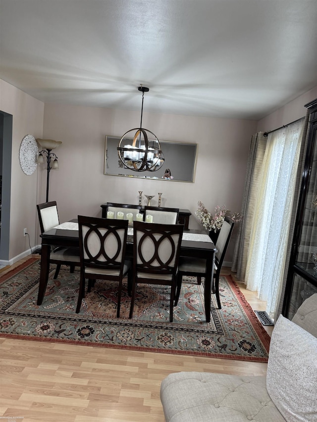 dining space featuring an inviting chandelier, visible vents, baseboards, and wood finished floors