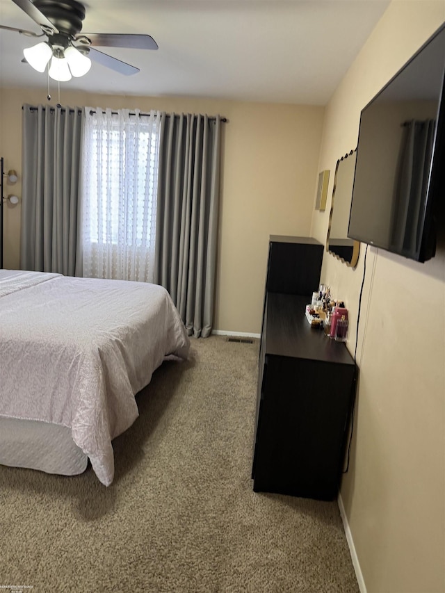 bedroom with light carpet, ceiling fan, visible vents, and baseboards