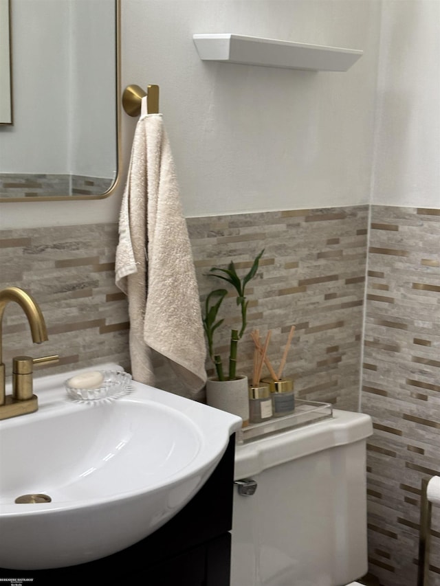 half bath featuring a sink, tile walls, and wainscoting