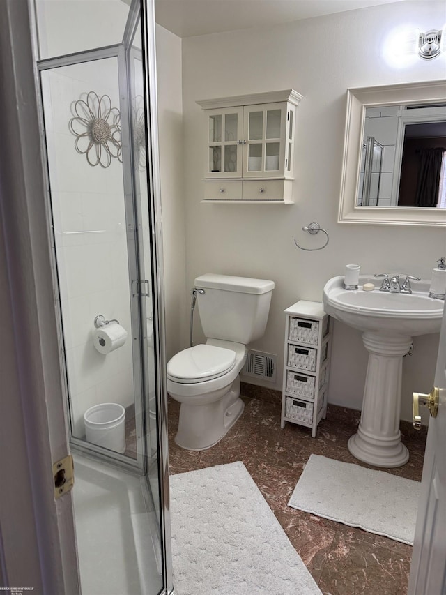 bathroom featuring baseboards, visible vents, toilet, a shower stall, and a sink