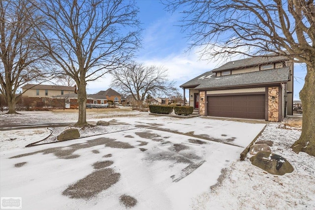 view of snow covered exterior with a garage and stone siding