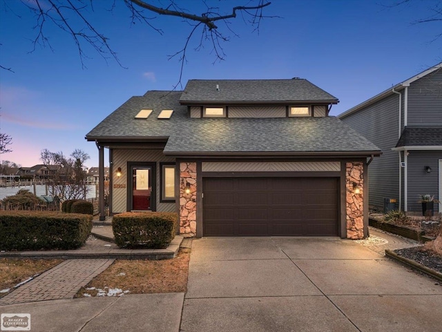 view of front of home with stone siding, a shingled roof, and driveway