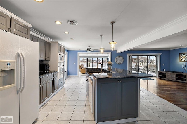 kitchen with light tile patterned floors, white refrigerator with ice dispenser, visible vents, and ornamental molding