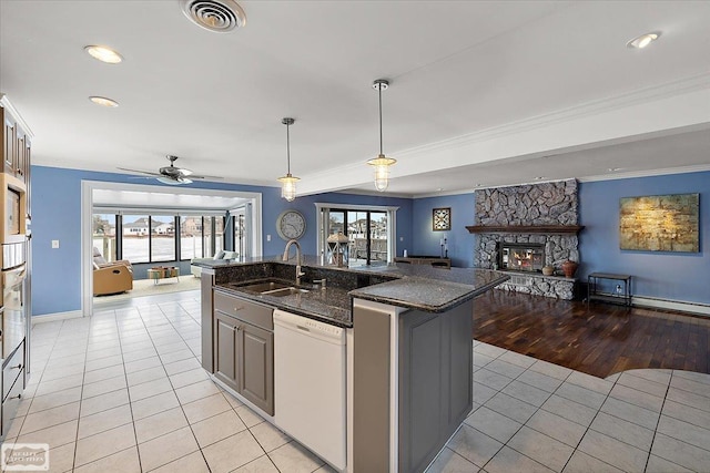 kitchen with visible vents, light tile patterned flooring, a sink, a stone fireplace, and dishwasher