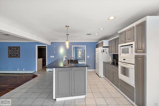 kitchen with a baseboard radiator, gray cabinetry, light tile patterned flooring, a kitchen island with sink, and white appliances