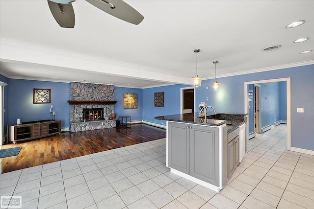 kitchen featuring a fireplace, light tile patterned floors, visible vents, ornamental molding, and a sink