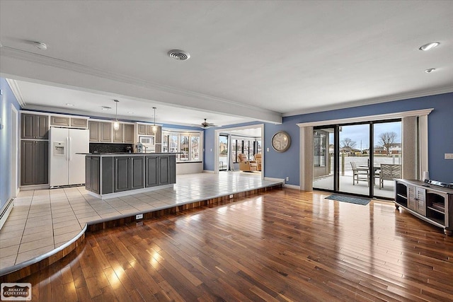 unfurnished living room featuring light wood-style floors, visible vents, ornamental molding, and baseboards