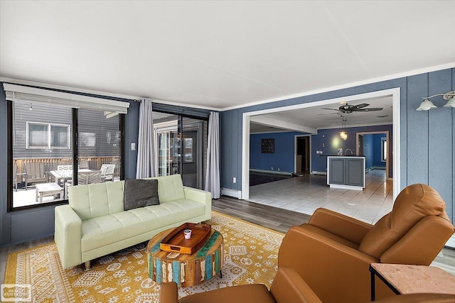 living room featuring wood finished floors, crown molding, and ceiling fan