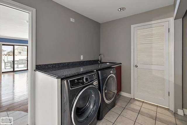 laundry room with light tile patterned floors, a sink, baseboards, cabinet space, and washing machine and clothes dryer