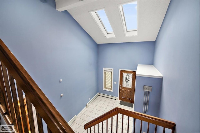 foyer entrance with lofted ceiling with skylight, tile patterned flooring, and baseboards