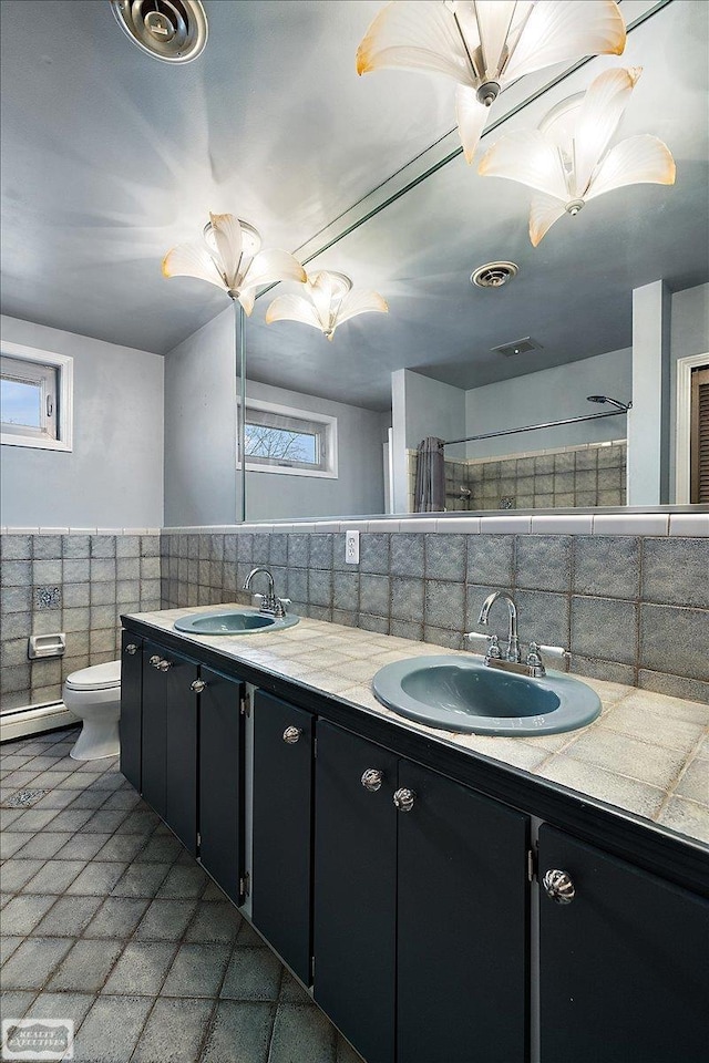 bathroom with double vanity, a wainscoted wall, visible vents, and a sink