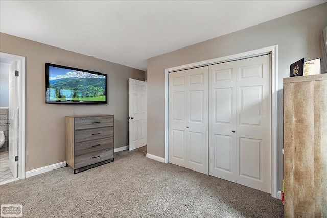 carpeted bedroom featuring a closet and baseboards