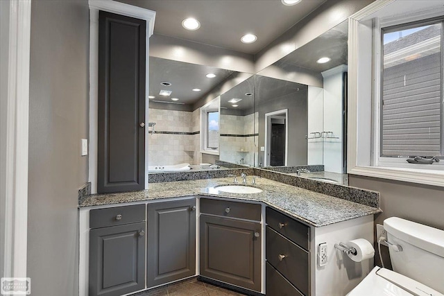 kitchen with light stone counters, recessed lighting, and a sink