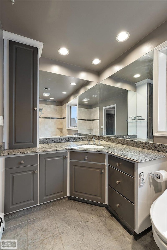 kitchen with recessed lighting, light stone counters, a sink, and gray cabinetry