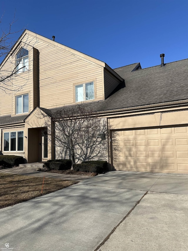 view of front facade with a shingled roof, driveway, and an attached garage