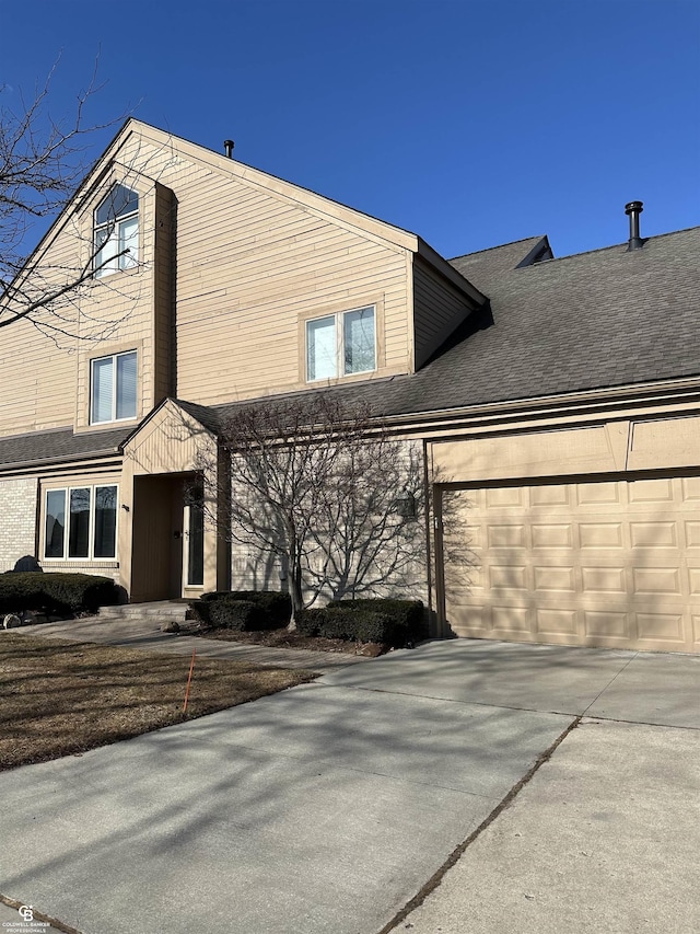 view of front facade with roof with shingles, driveway, and an attached garage