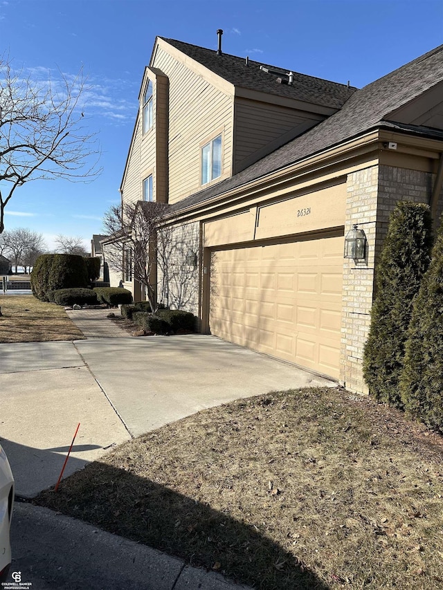 view of side of property with a garage, concrete driveway, and brick siding