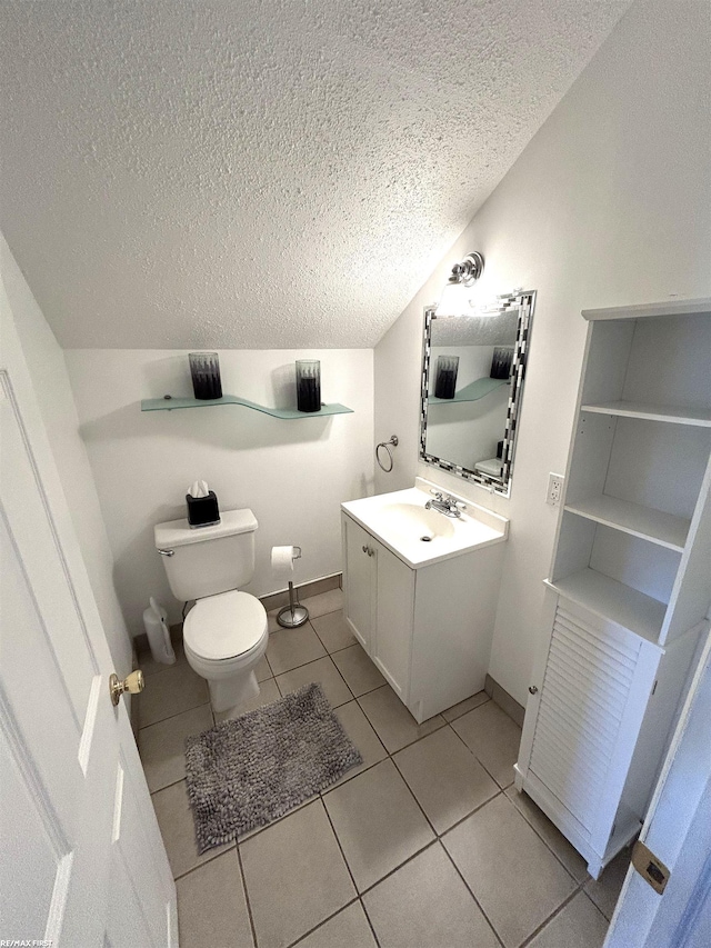 half bath featuring toilet, a textured ceiling, tile patterned flooring, vanity, and vaulted ceiling