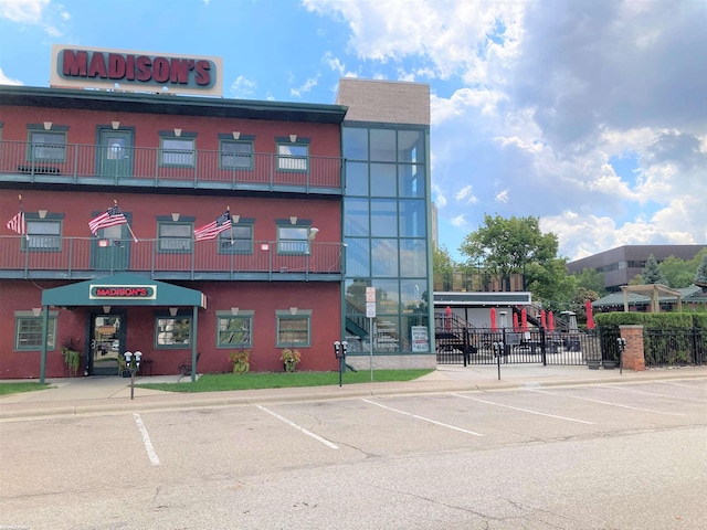 view of building exterior featuring uncovered parking and fence