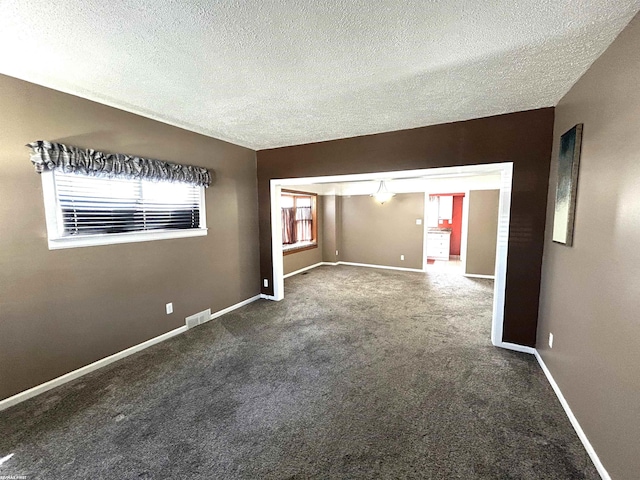 carpeted empty room with visible vents, baseboards, and a textured ceiling