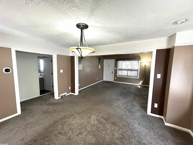 interior space featuring visible vents, carpet, baseboards, and a textured ceiling