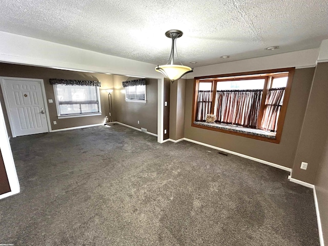 interior space featuring visible vents, a textured ceiling, baseboards, and carpet