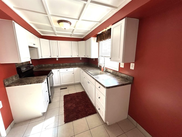 kitchen with range with electric cooktop, a sink, dark countertops, white cabinetry, and baseboards