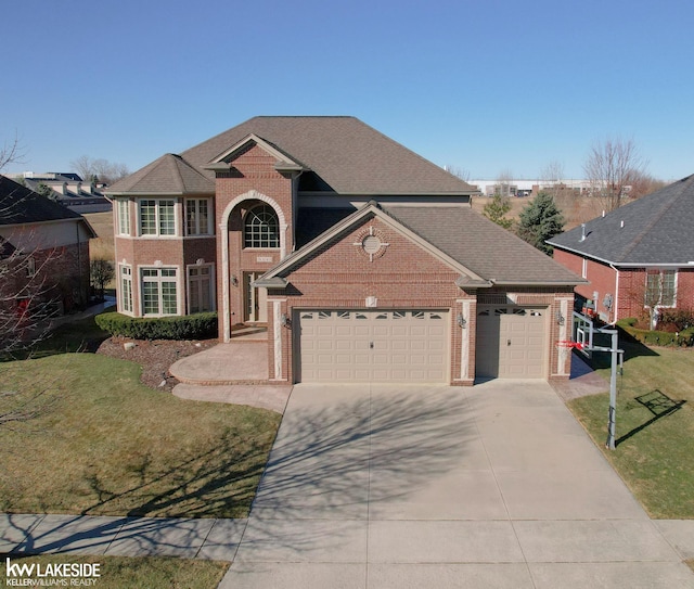 traditional-style house featuring brick siding, a shingled roof, a front yard, a garage, and driveway