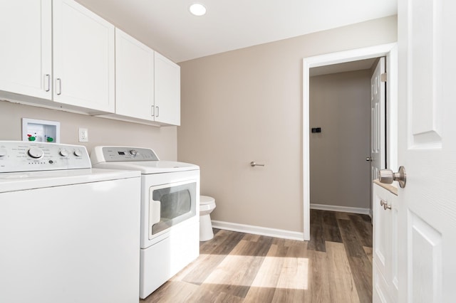 clothes washing area featuring washing machine and dryer, laundry area, baseboards, and light wood finished floors