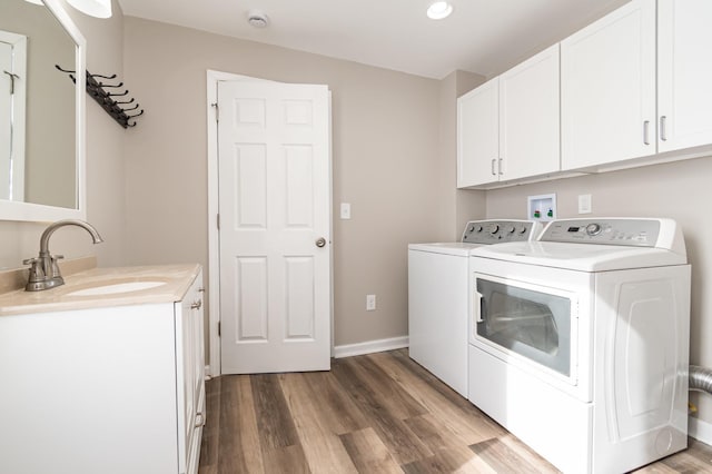 laundry room featuring cabinet space, a sink, separate washer and dryer, wood finished floors, and baseboards