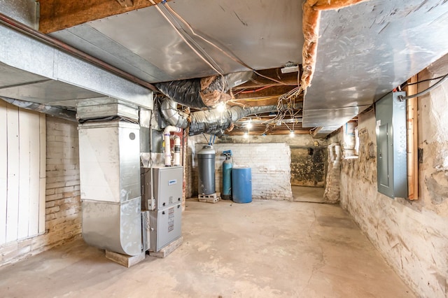 unfinished basement featuring electric panel and heating unit