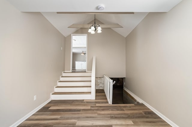 stairway featuring a notable chandelier, wood finished floors, lofted ceiling, and baseboards