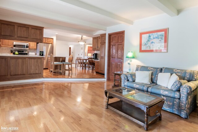 living area featuring light wood finished floors and beam ceiling