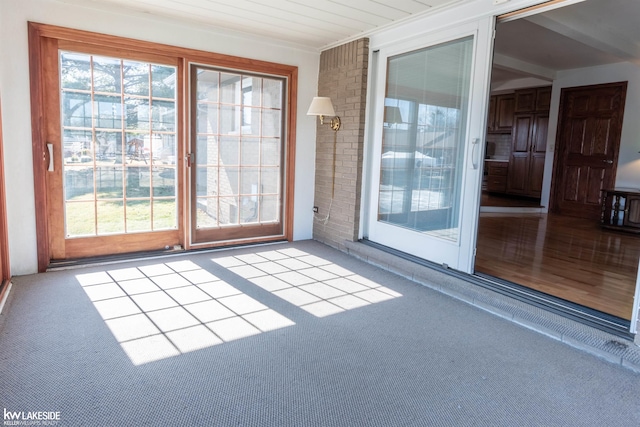 doorway with ornamental molding and carpet